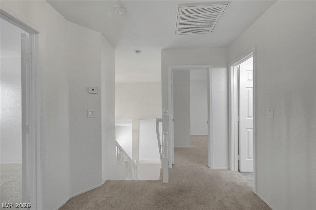 31 Antero Drive, Henderson, NV 89074 An inviting carpeted hallway leads to individual rooms, offering a clear and functional layout.