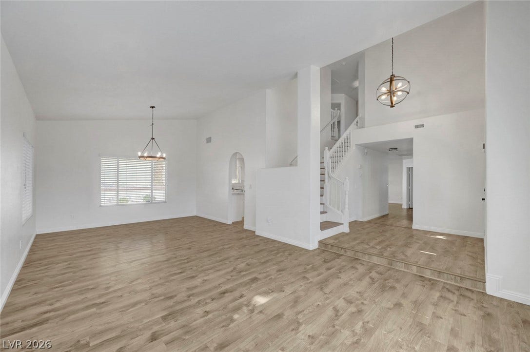 31 Antero Drive, Henderson, NV 89074 Enter into a vast living space featuring towering ceilings and wide plank flooring, with a grand staircase visible.