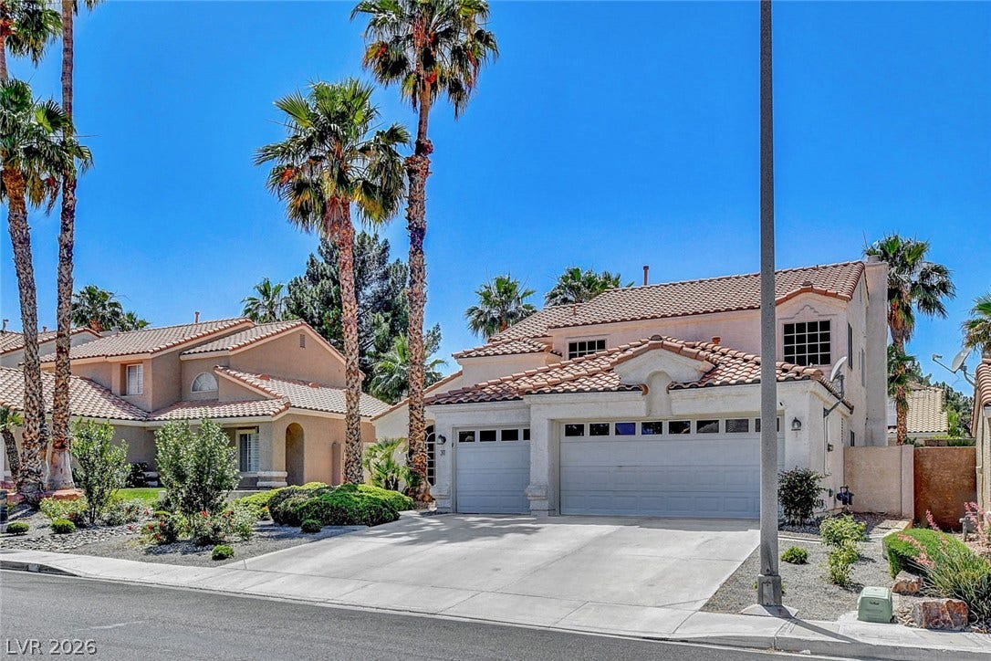 31 Antero Drive, Henderson, NV 89074 A terracotta-roofed residence with an integrated two-car garage is framed by stately palm trees, enhancing its desert-friendly facade.