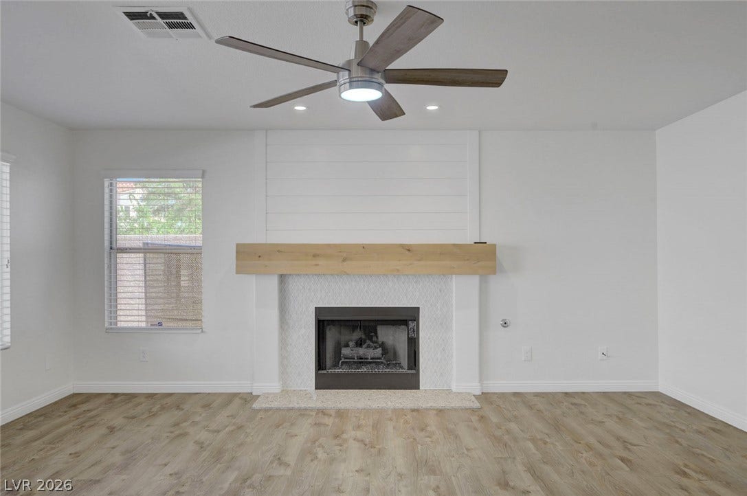 31 Antero Drive, Henderson, NV 89074 A refined living space showcasing a fireplace with a sleek hearth and light wood flooring.
