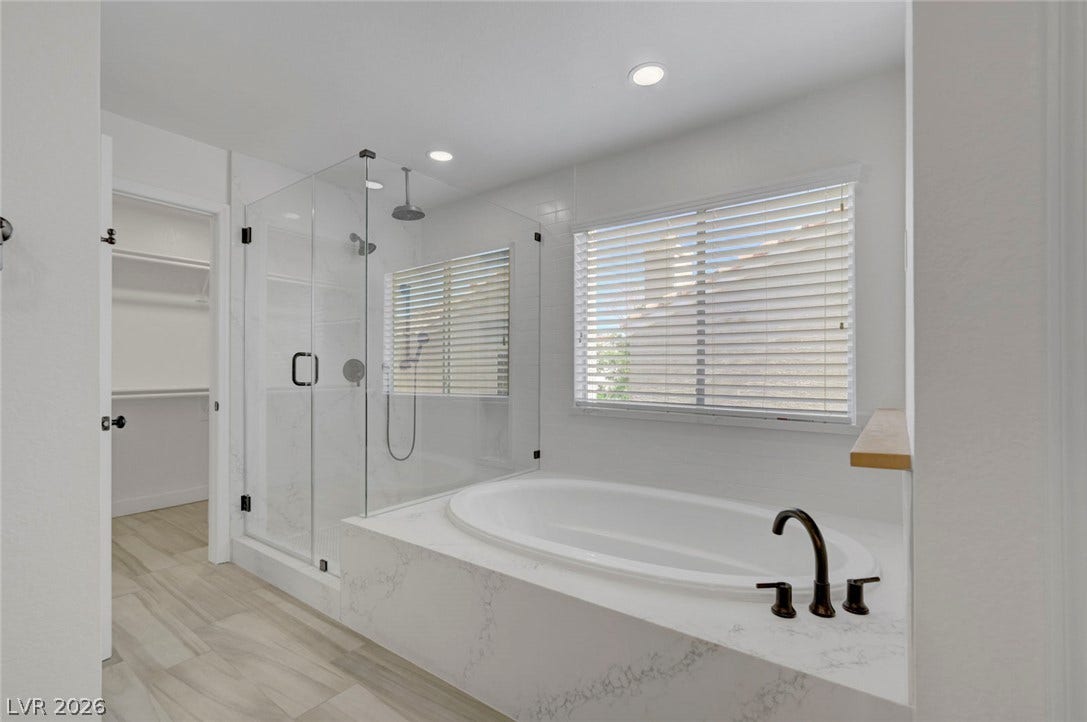 31 Antero Drive, Henderson, NV 89074 Luxurious bathroom retreat, featuring an inviting soaking tub and a sleek glass-enclosed shower.