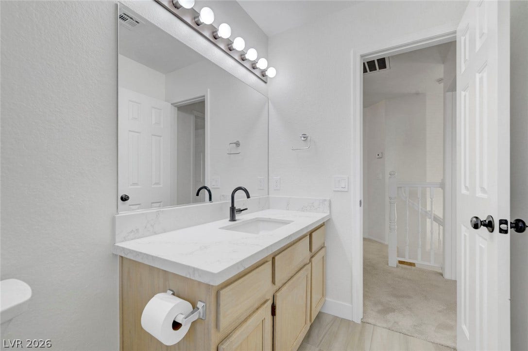 31 Antero Drive, Henderson, NV 89074 A well-lit vanity with pristine white counters and contemporary black fixtures, offering functional elegance.