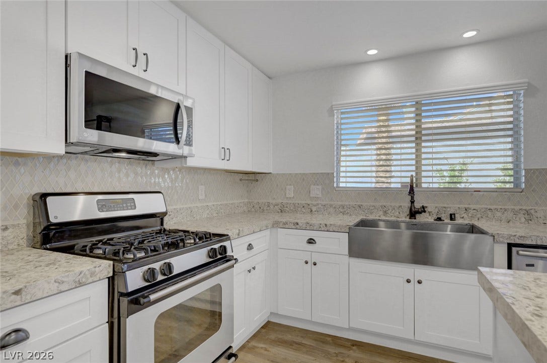 31 Antero Drive, Henderson, NV 89074 A well-lit kitchen with sleek stainless steel appliances, ample white cabinetry, and durable stone countertops.