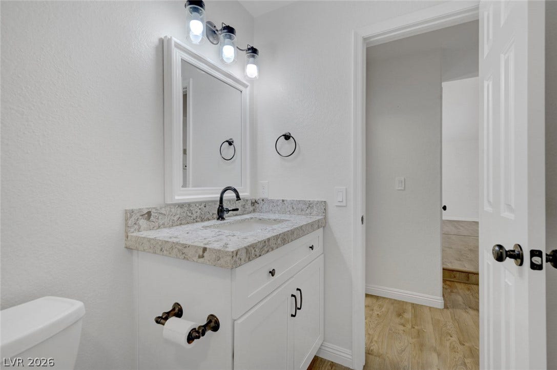 31 Antero Drive, Henderson, NV 89074 White vanity with a marble counter and contemporary fixtures elevates this well-lit bath space.