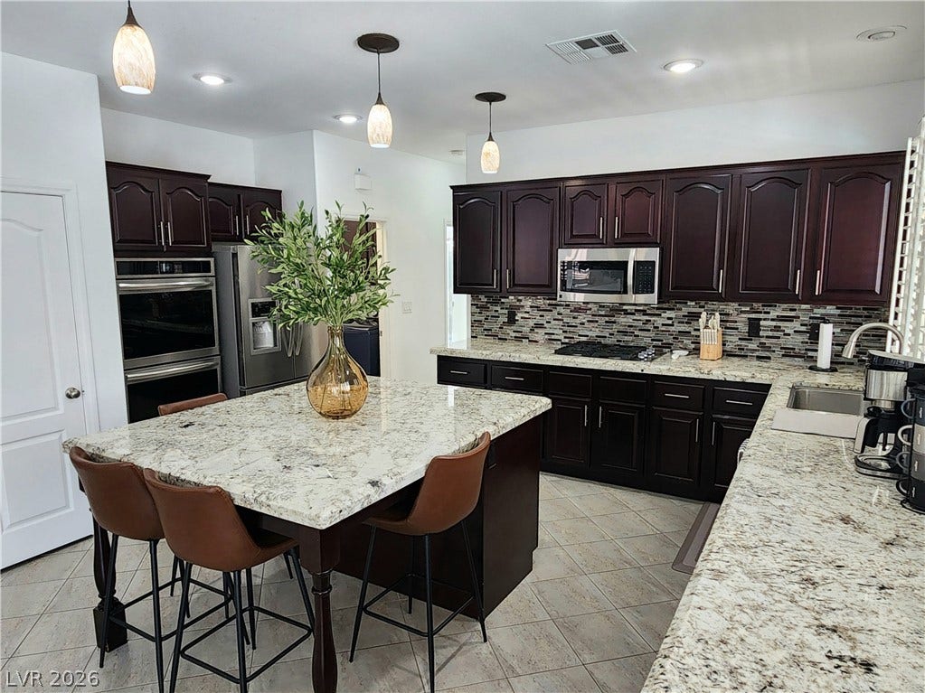 2743 Peekskill Avenue, Henderson, NV 89052 This spacious kitchen offers ample granite counter space, dark wood cabinetry, and a convenient island with seating.