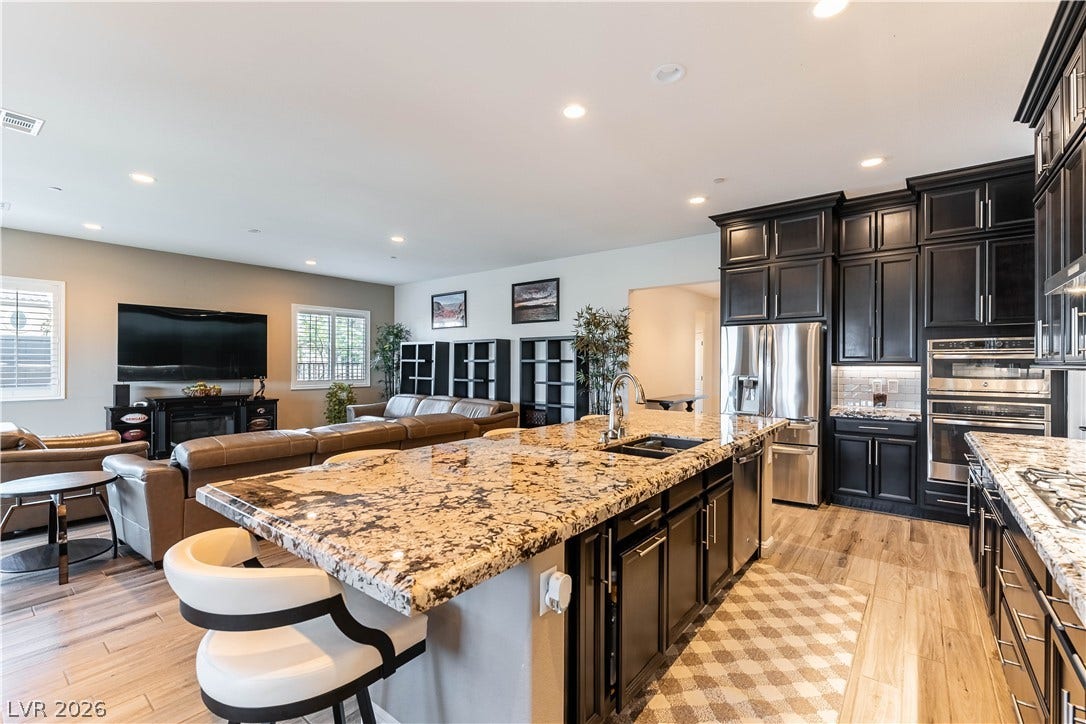 900 San Laurent Court, Henderson, NV 89012 An open concept living area boasts a gourmet kitchen island with granite counters and rich dark cabinetry.