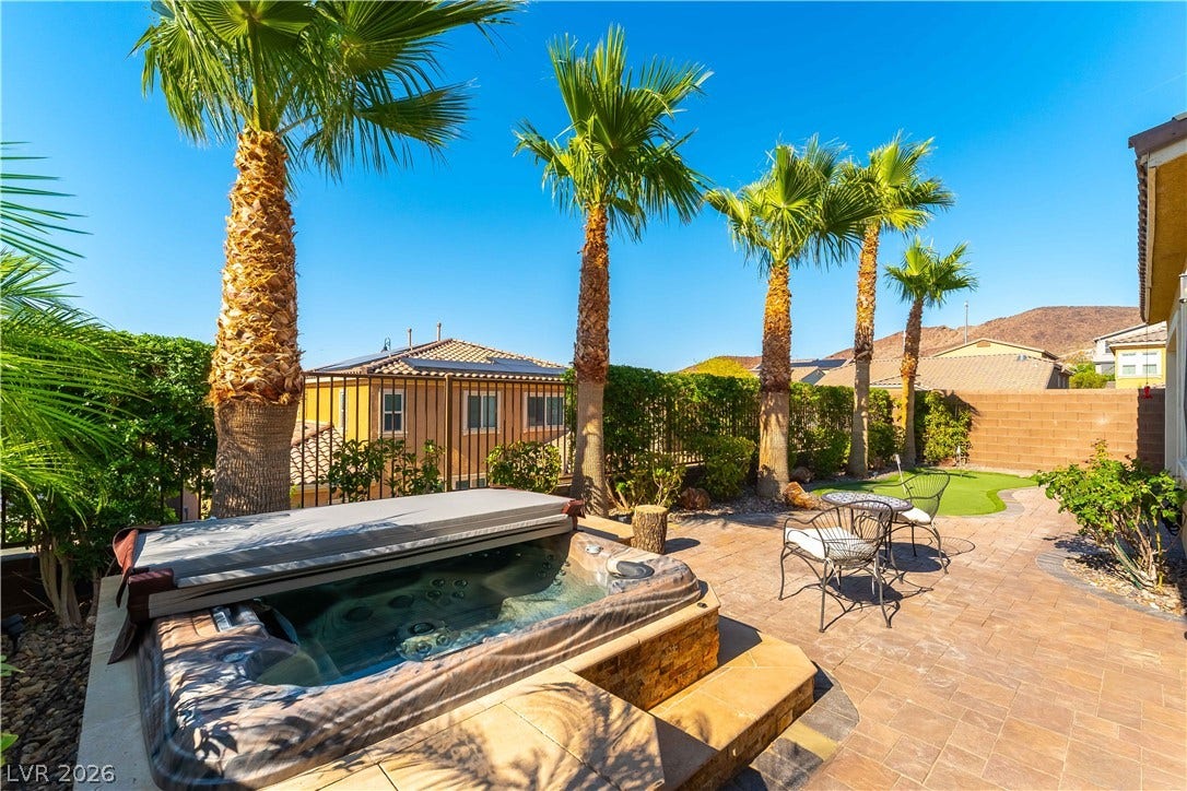900 San Laurent Court, Henderson, NV 89012 A private backyard oasis features a hot tub, a manicured green space, and towering palm trees.
