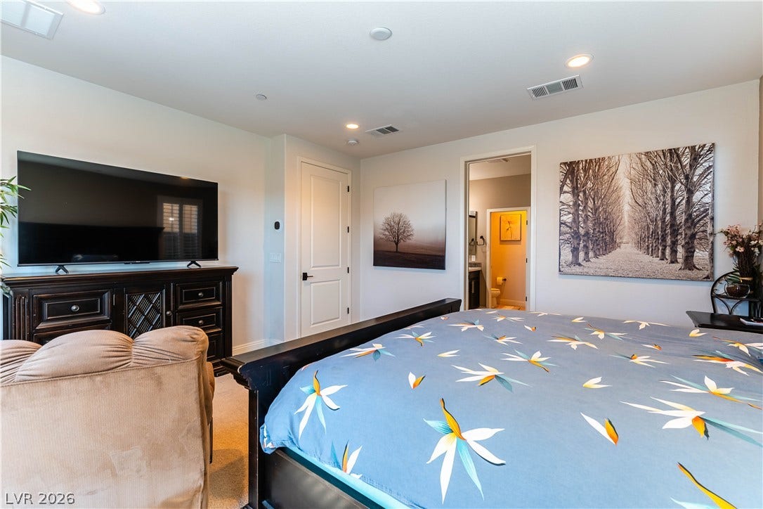 900 San Laurent Court, Henderson, NV 89012 A well-lit primary bedroom offers plush carpeting and convenient access to a private bathroom.