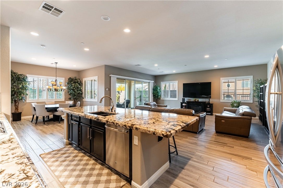 900 San Laurent Court, Henderson, NV 89012 An open floorplan seamlessly connects the kitchen, dining area, and living room, bathed in natural light from ample windows.