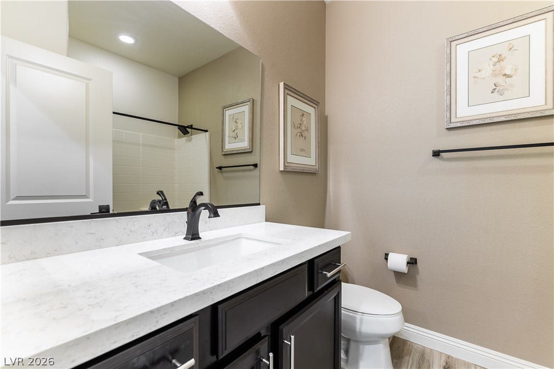 900 San Laurent Court, Henderson, NV 89012 A well-appointed bathroom features a dark wood vanity, white countertop, and a shower with clean tile.