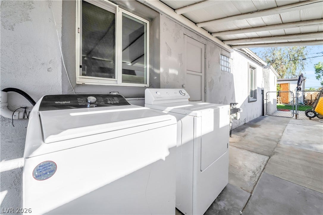 An outdoor laundry area with washer and dryer provides practical utility next to the main building.
