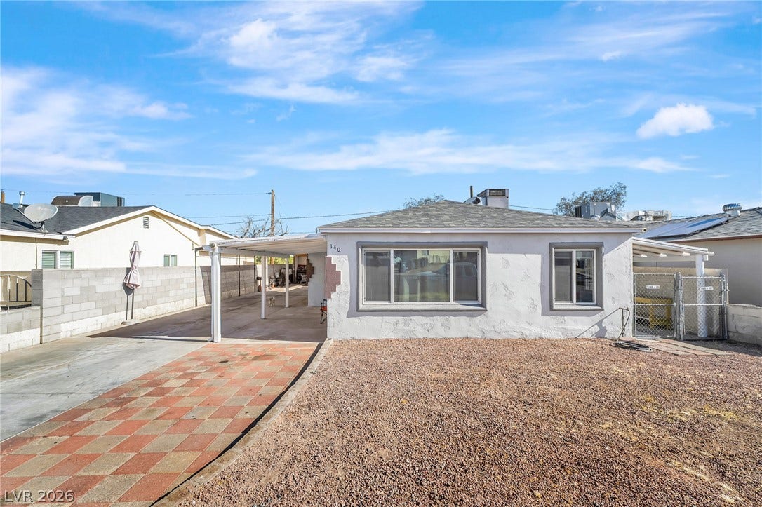 A modest home with a checkered driveway and a gravel front yard, offering practical outdoor living.
