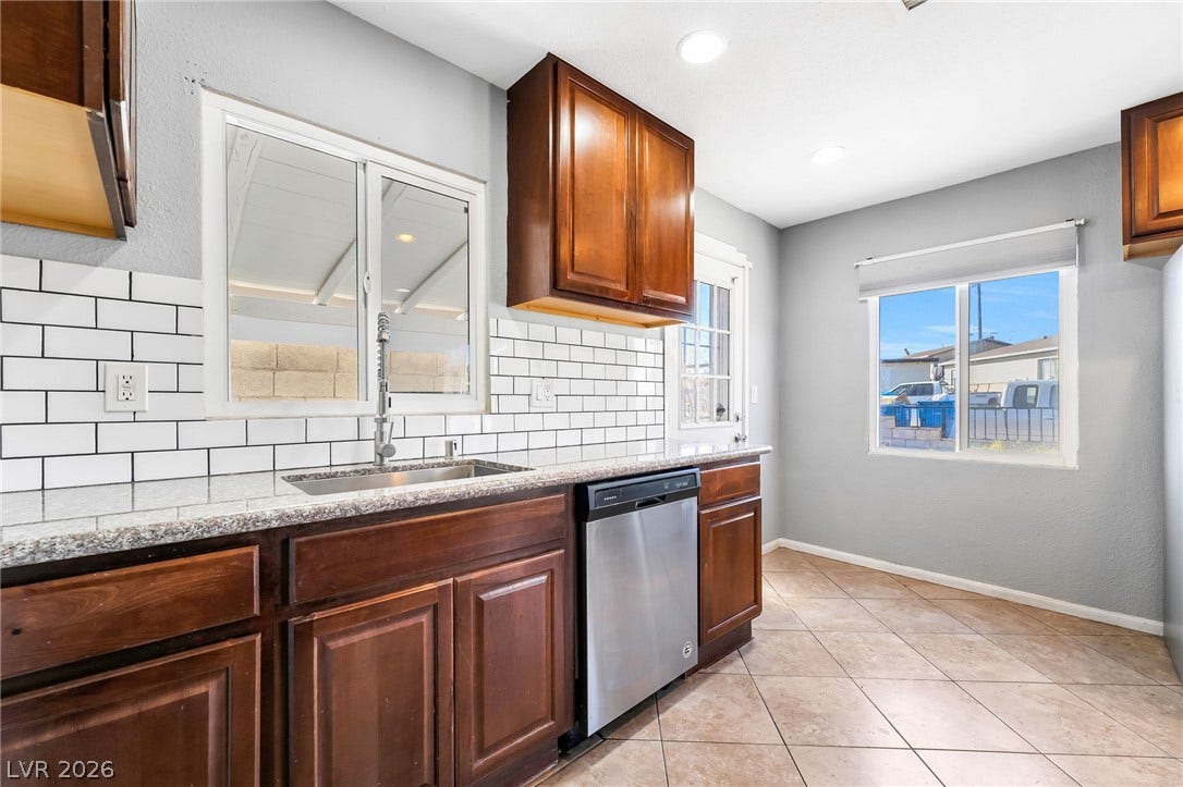 A streamlined kitchen design showcases rich cabinetry, granite countertops, and modern appliances.