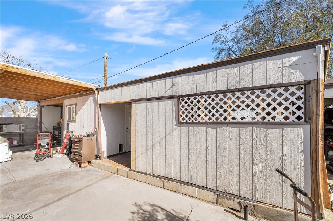 An ideal workshop or storage area featuring durable siding and an adjacent covered carport.