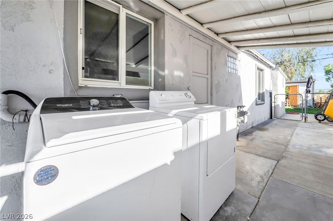 An outdoor laundry setup with appliances offers convenient utility access near a fenced yard.