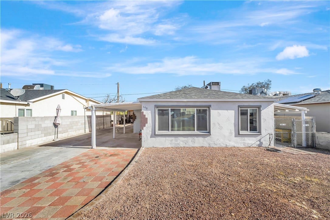 A well-maintained stucco facade with a covered carport provides practical curb appeal.