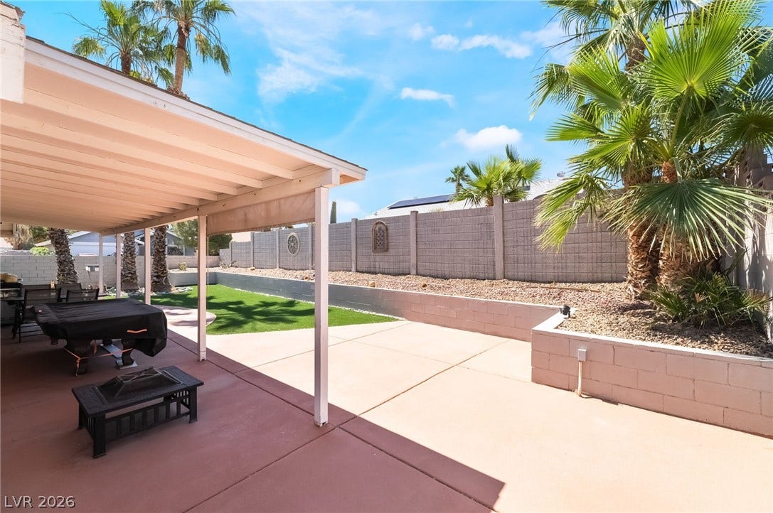 3111 Belvedere Drive, Henderson, NV 89014 A spacious covered patio provides a delightful outdoor living area with a lush green lawn and mature palm trees.