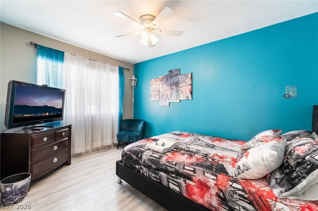 3111 Belvedere Drive, Henderson, NV 89014 Natural light filters through the window into this inviting bedroom, featuring light-colored flooring and a ceiling fan for comfort.