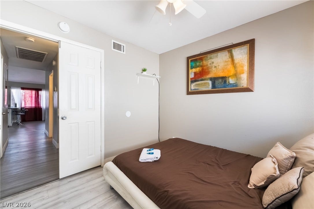 3111 Belvedere Drive, Henderson, NV 89014 A well-appointed sleeping area features a ceiling fan, light wood flooring, and a crisp white door leading to additional living spaces.