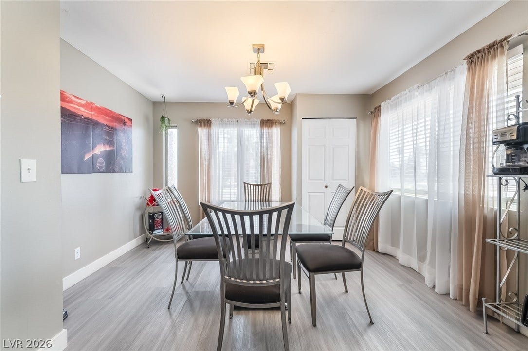 3111 Belvedere Drive, Henderson, NV 89014 A graceful dining room boasts wide plank flooring and a stylish chandelier, offering an ideal setting for meals.