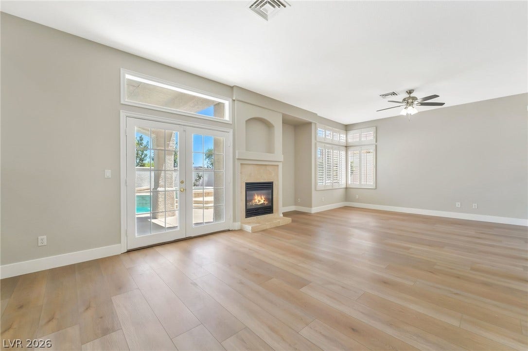 1278 Autumn Wind Way, Henderson, NV 89052 A refined living space showcasing a fireplace and French doors opening to an inviting outdoor pool area.