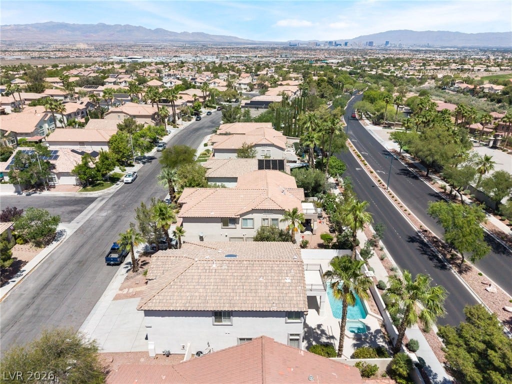 1278 Autumn Wind Way, Henderson, NV 89052 An aerial perspective reveals a vibrant neighborhood with tile-roofed homes, verdant landscaping, and a distant city skyline.