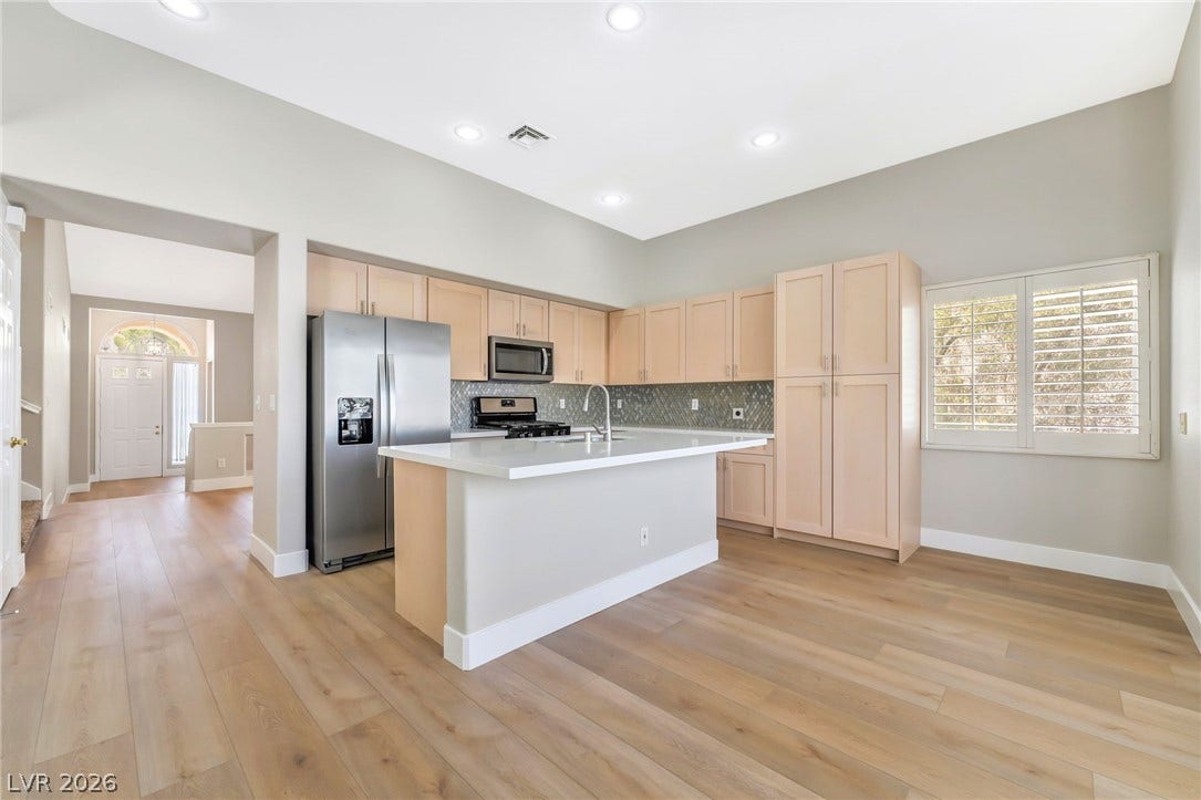 1278 Autumn Wind Way, Henderson, NV 89052 A well-appointed kitchen features stainless steel appliances, a center island, and rich hardwood flooring, flowing into an inviting entrance foyer.