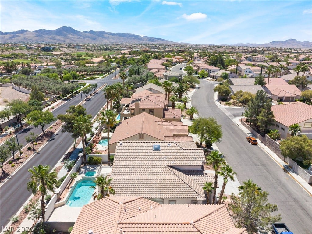 1278 Autumn Wind Way, Henderson, NV 89052 An aerial perspective reveals a vibrant neighborhood with desert landscaping, private pools, and a commanding mountain view.