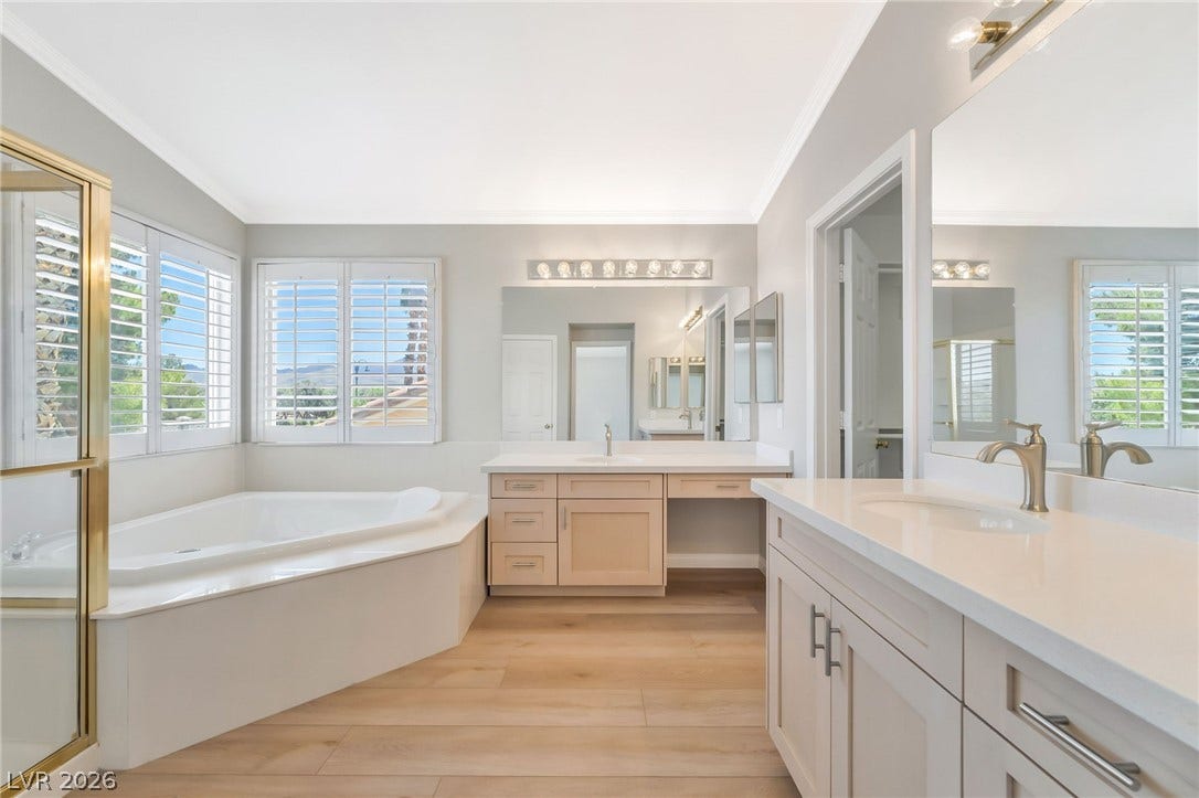 1278 Autumn Wind Way, Henderson, NV 89052 Unwind in the primary bath, featuring a generous soaking tub, dual vanities, and warm wood flooring.