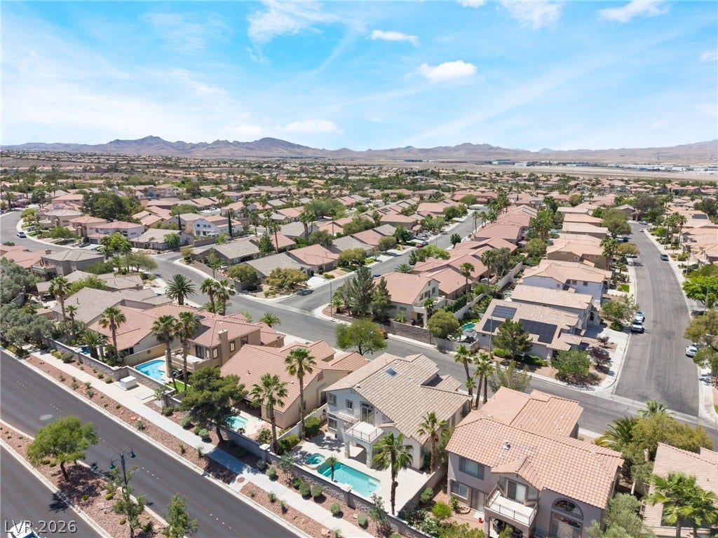 1278 Autumn Wind Way, Henderson, NV 89052 An aerial perspective reveals a vibrant neighborhood with homes, pools, and distant mountains.