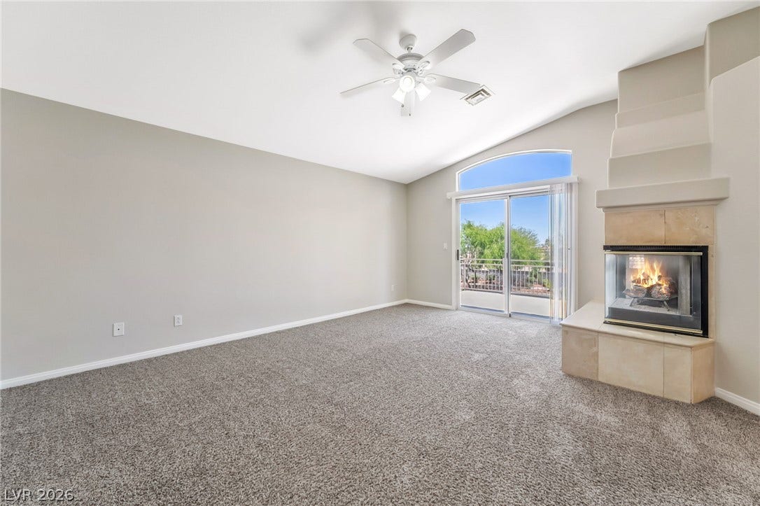 1278 Autumn Wind Way, Henderson, NV 89052 A spacious room features a cozy corner fireplace and sliding glass doors that open to a scenic view.
