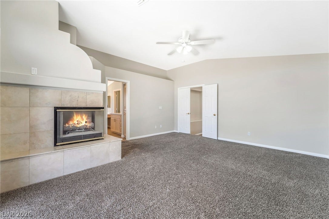 1278 Autumn Wind Way, Henderson, NV 89052 A spacious primary bedroom features a cozy fireplace, vaulted ceilings, and plush carpet.