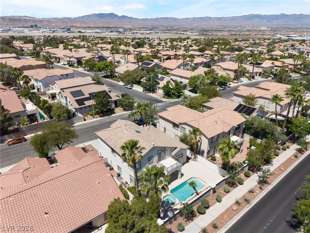 1278 Autumn Wind Way, Henderson, NV 89052 An aerial perspective showcases a residential neighborhood nestled near mountains, with several homes featuring private pools.