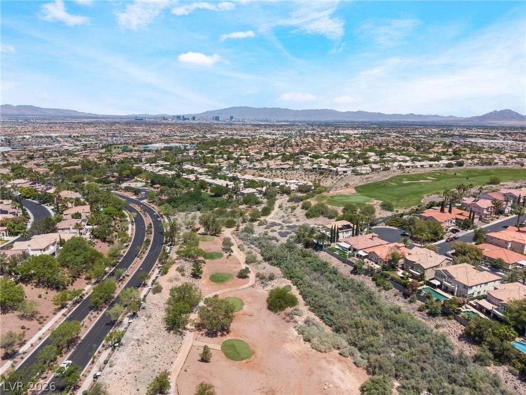 1278 Autumn Wind Way, Henderson, NV 89052 An aerial panorama reveals a vast residential community nestled against distant mountains, featuring a golf course and meandering roads.