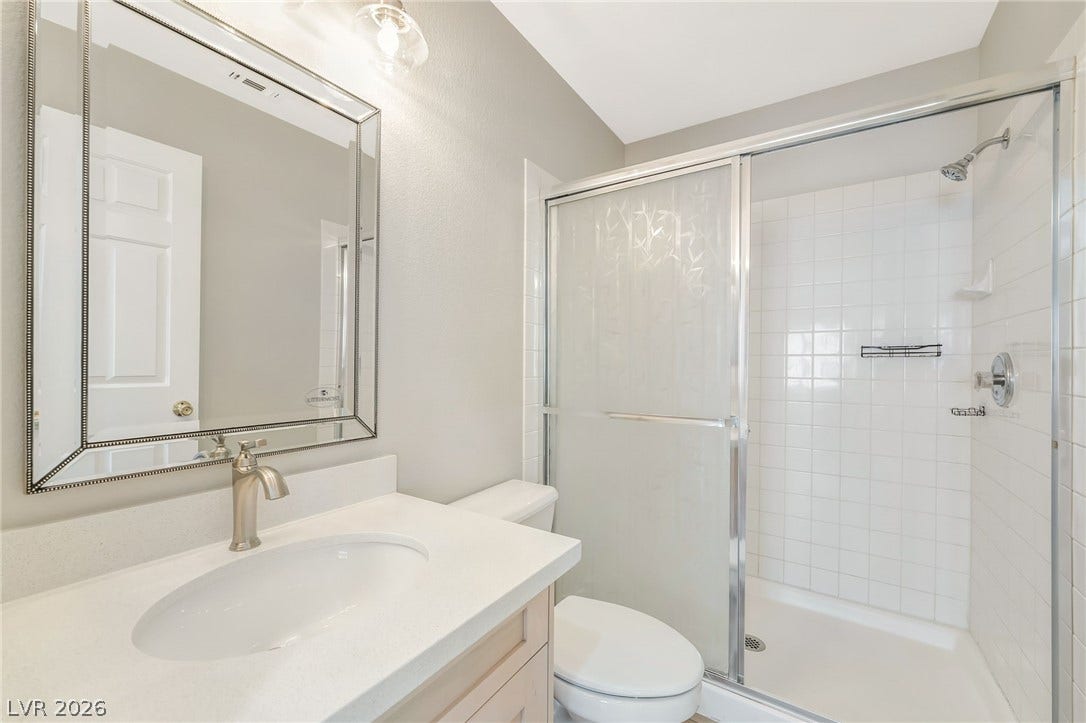 1278 Autumn Wind Way, Henderson, NV 89052 A well-appointed bathroom features a single vanity, a sleek toilet, and a glass-enclosed shower.