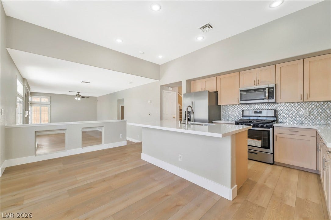 1278 Autumn Wind Way, Henderson, NV 89052 A streamlined kitchen layout includes an eat-in island, stainless appliances, and luminous light wood flooring.