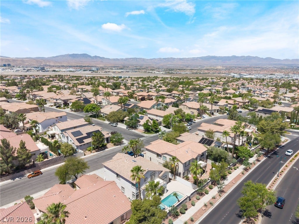 1278 Autumn Wind Way, Henderson, NV 89052 An aerial perspective reveals a vibrant neighborhood under an expansive sky, with distant mountains framing the horizon.