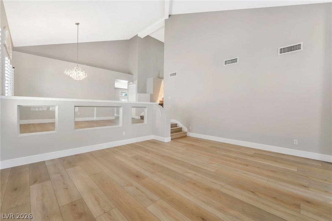 1278 Autumn Wind Way, Henderson, NV 89052 Natural wood flooring complements vaulted ceilings and an upper-level chandelier in this bright living space.