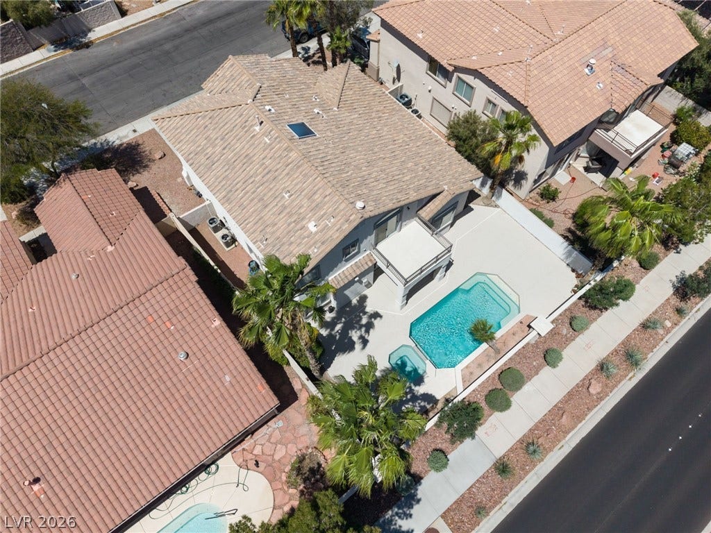 1278 Autumn Wind Way, Henderson, NV 89052 An aerial perspective showcases a vibrant backyard pool with surrounding landscaping and adjacent neighborhood streets.