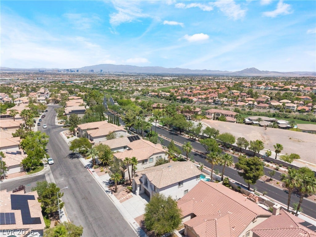 1278 Autumn Wind Way, Henderson, NV 89052 An aerial perspective reveals a vibrant neighborhood with a city skyline and mountains in the distance.
