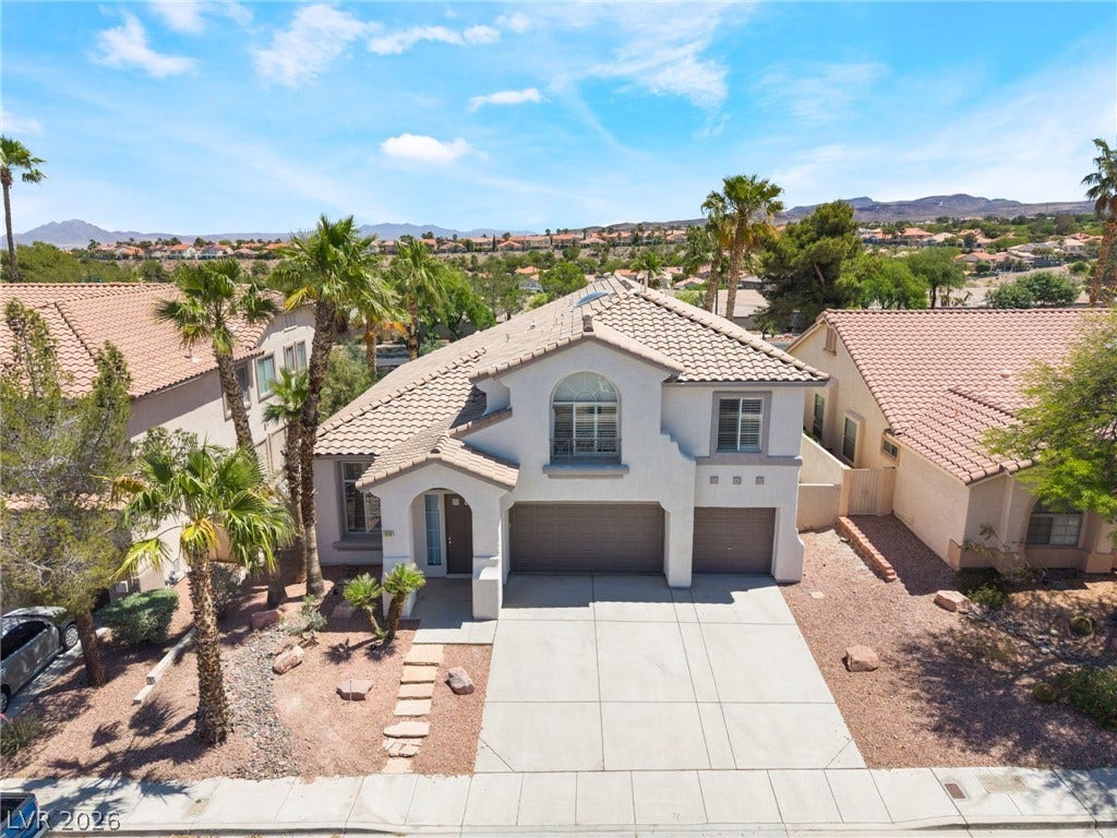 1278 Autumn Wind Way, Henderson, NV 89052 A desert oasis with inviting curb appeal, featuring lush palm trees and distant mountain vistas.