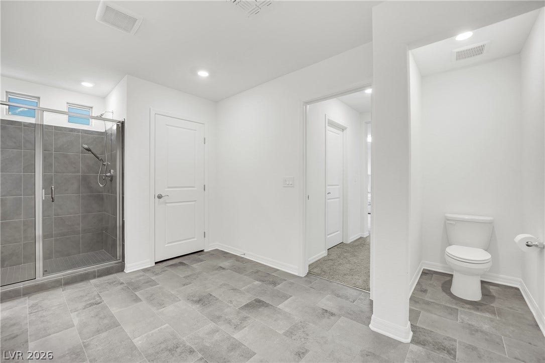 7710 Weekes Court, Las Vegas, NV 89113 A glass-enclosed walk-in shower highlights this modern bathroom with neutral tile flooring.