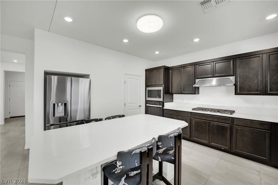 7710 Weekes Court, Las Vegas, NV 89113 Dark cabinetry beautifully contrasts with a spacious light island and neutral tile flooring.