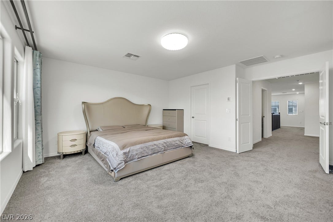 7710 Weekes Court, Las Vegas, NV 89113 An open doorway leads from this carpeted bedroom into a wide hallway.