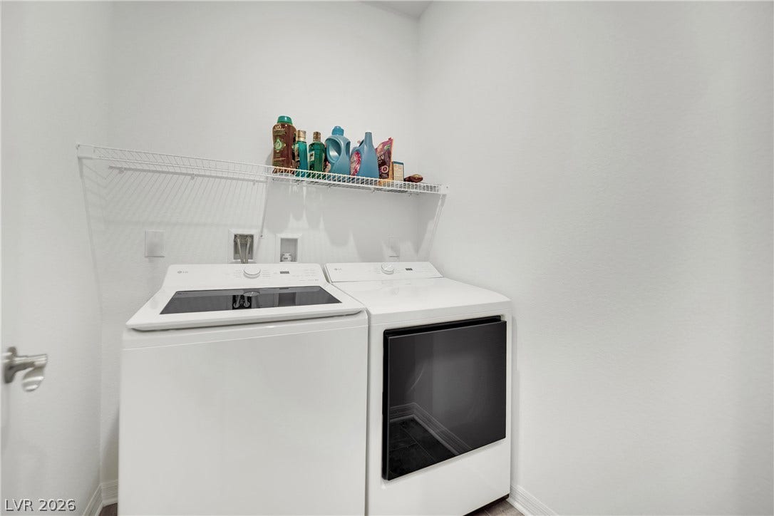 7710 Weekes Court, Las Vegas, NV 89113 A dedicated laundry space features clean walls and a practical wire storage shelf above appliances.