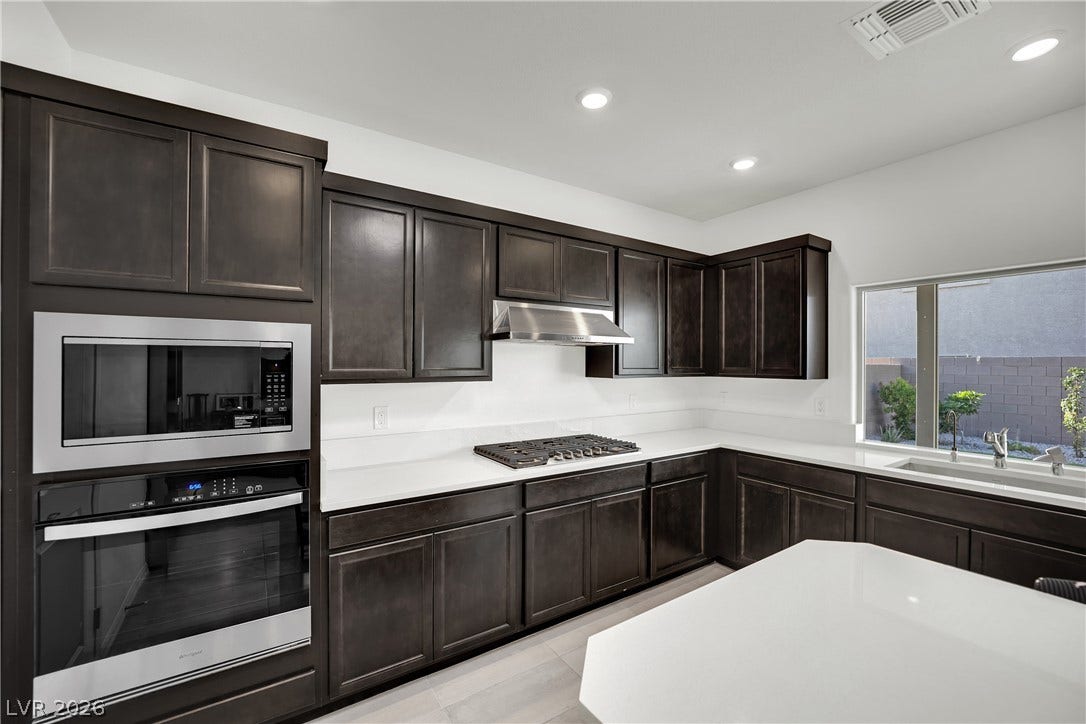 7710 Weekes Court, Las Vegas, NV 89113 Rich dark cabinetry contrasts beautifully with crisp solid-surface countertops in this modern culinary space.