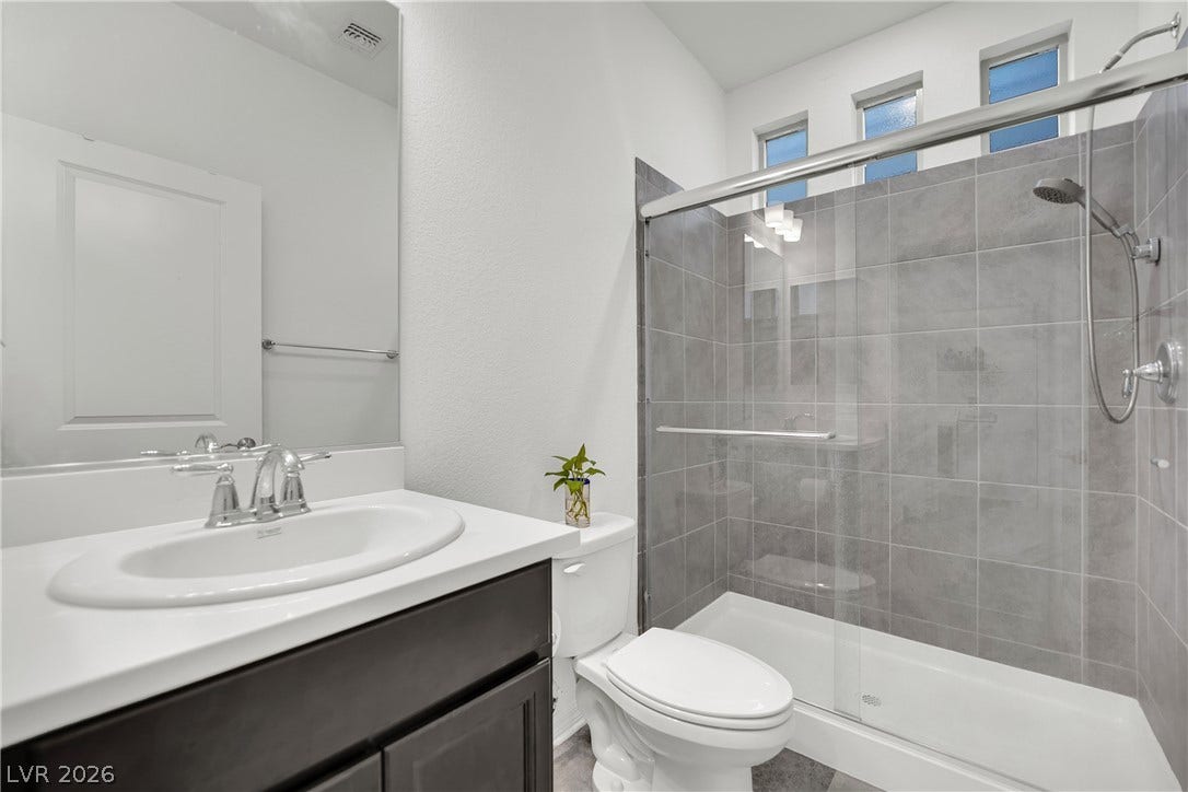 7710 Weekes Court, Las Vegas, NV 89113 Tiled walk-in shower with sliding glass doors complements the modern vanity station.