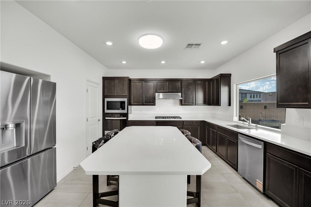 7710 Weekes Court, Las Vegas, NV 89113 Dark cabinetry beautifully contrasts with white solid-surface countertops and an oversized central island.