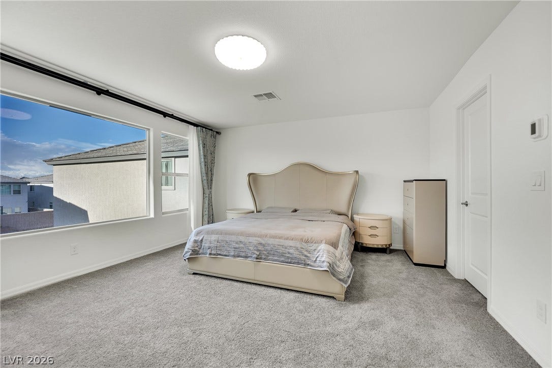 7710 Weekes Court, Las Vegas, NV 89113 Large windows fill this carpeted bedroom with natural light.