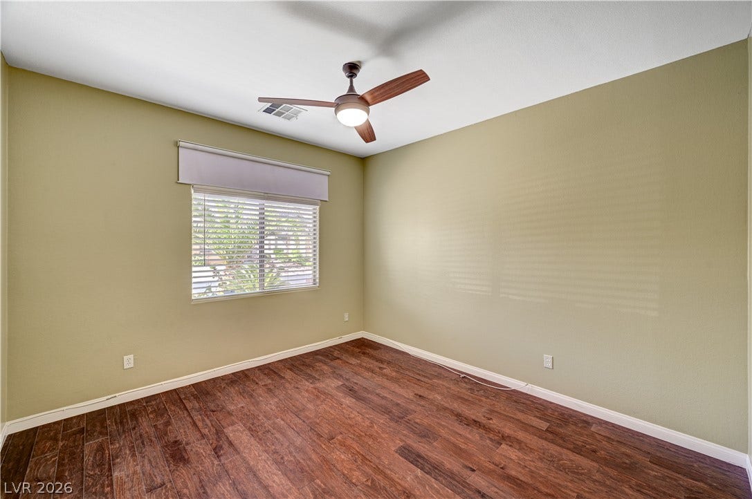 115 Cora Hills Court, Las Vegas, NV 89148 A well-lit bedroom featuring rich hardwood flooring and a functional ceiling fan.